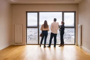 Couple visitant un logement avec une agente immobilière pour préparer un dossier de location en France ou à l’étranger